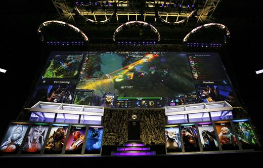 The crowd at KeyArena watches the action on giant screens while teams compete from booths below at the “Dota 2″ tournament The International